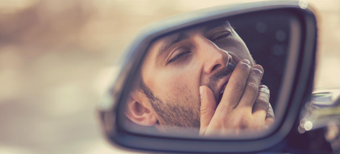 Tired driver yawning in side mirror