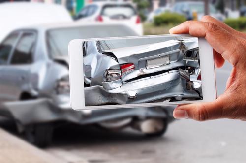 A person taking photos of their car after a hit and run accident.