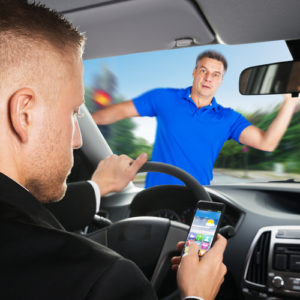 Image is of a man texting while driving and about to hit a pedestrian, and will need to call a Lackawanna distracted driving accident lawyer